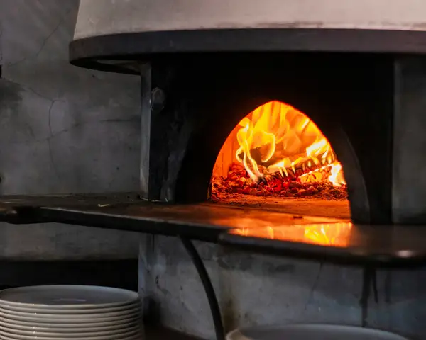 A pizza baking inside a hot oven on a stone surface, illustrating pizza stone vs steel performance
