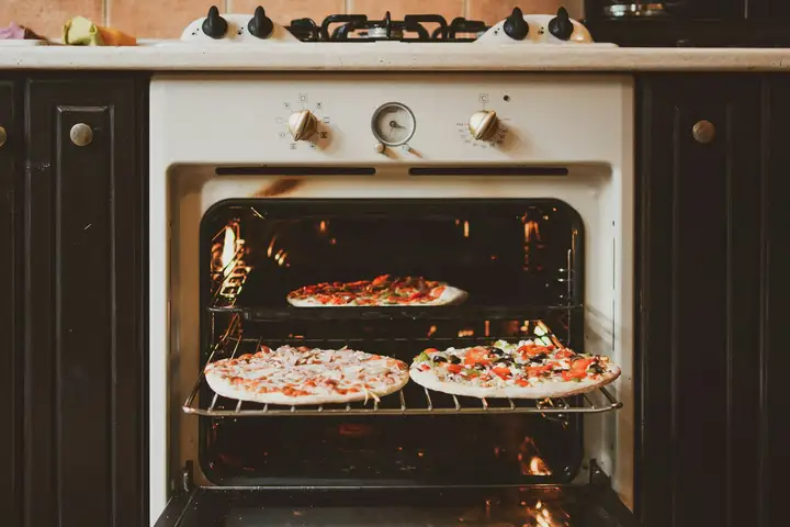 Homemade pizzas baking in a home oven, the setup where a preheated pizza stone gives the crispest crust