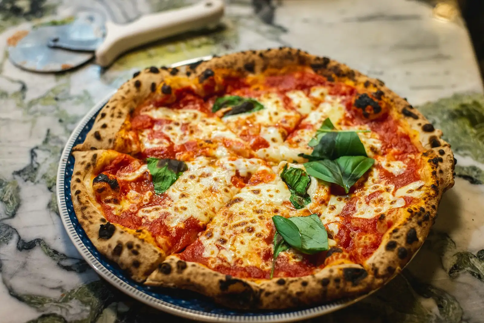 Pizza baking in a high-temperature oven with flames visible, showing the heat range needed for Neapolitan style pizza