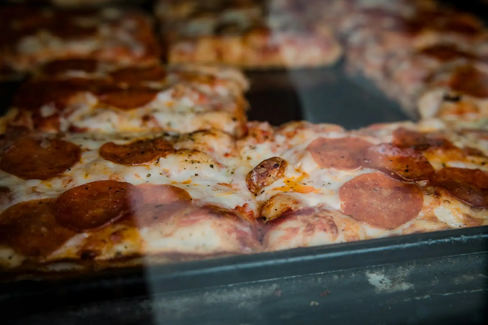 A thin-crust pepperoni pizza cut into squares in the tavern-cut style on a metal tray