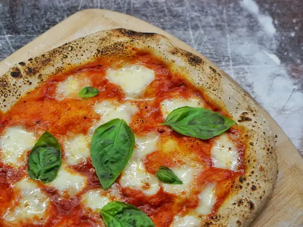 Sourdough pizza dough with an open, airy crumb and blistered fermented crust on a wooden surface