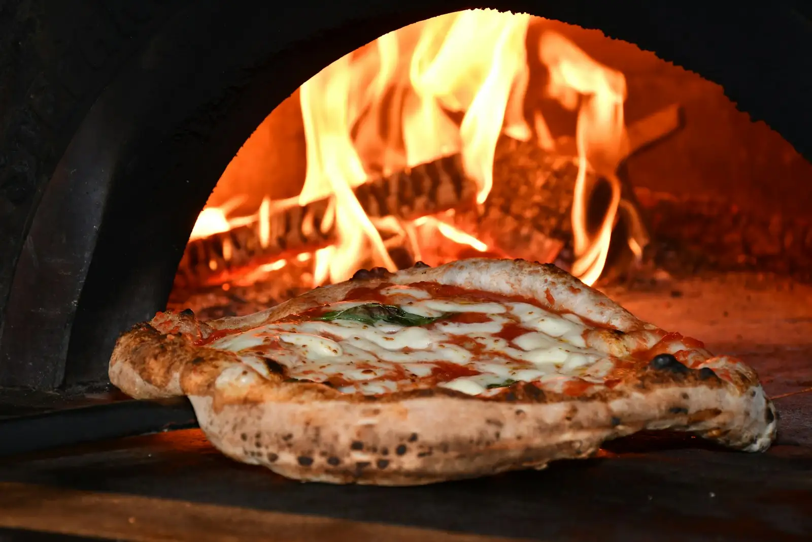 A pizza with a blistered, leopard-spotted crust and a browned bottom, the result a pizza steel produces