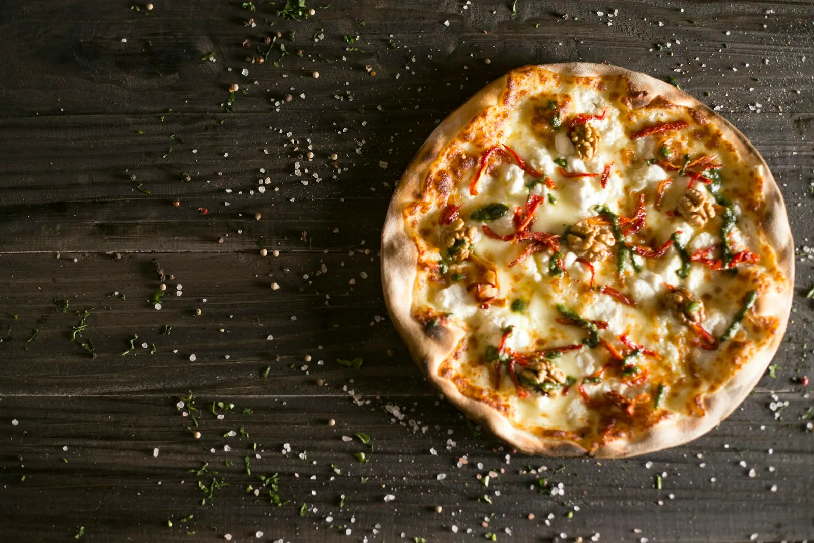 A baked pizza showing why low-moisture mozzarella is the best cheese for pizza, melted and browned on a dark board