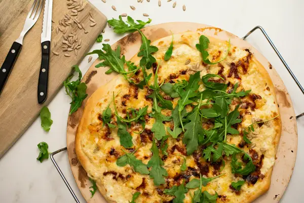 A baked pizza on a wooden cutting board, the result of a properly cared-for pizza stone