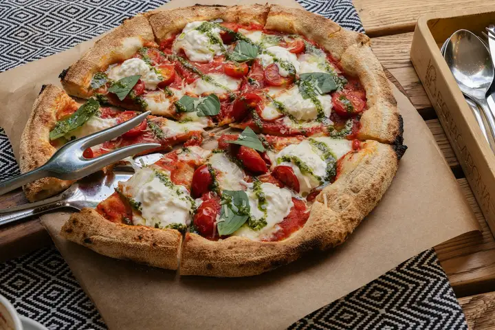 A charred, blistered pizza fresh off high heat, the kind of crisp crust you get cooking pizza on the grill