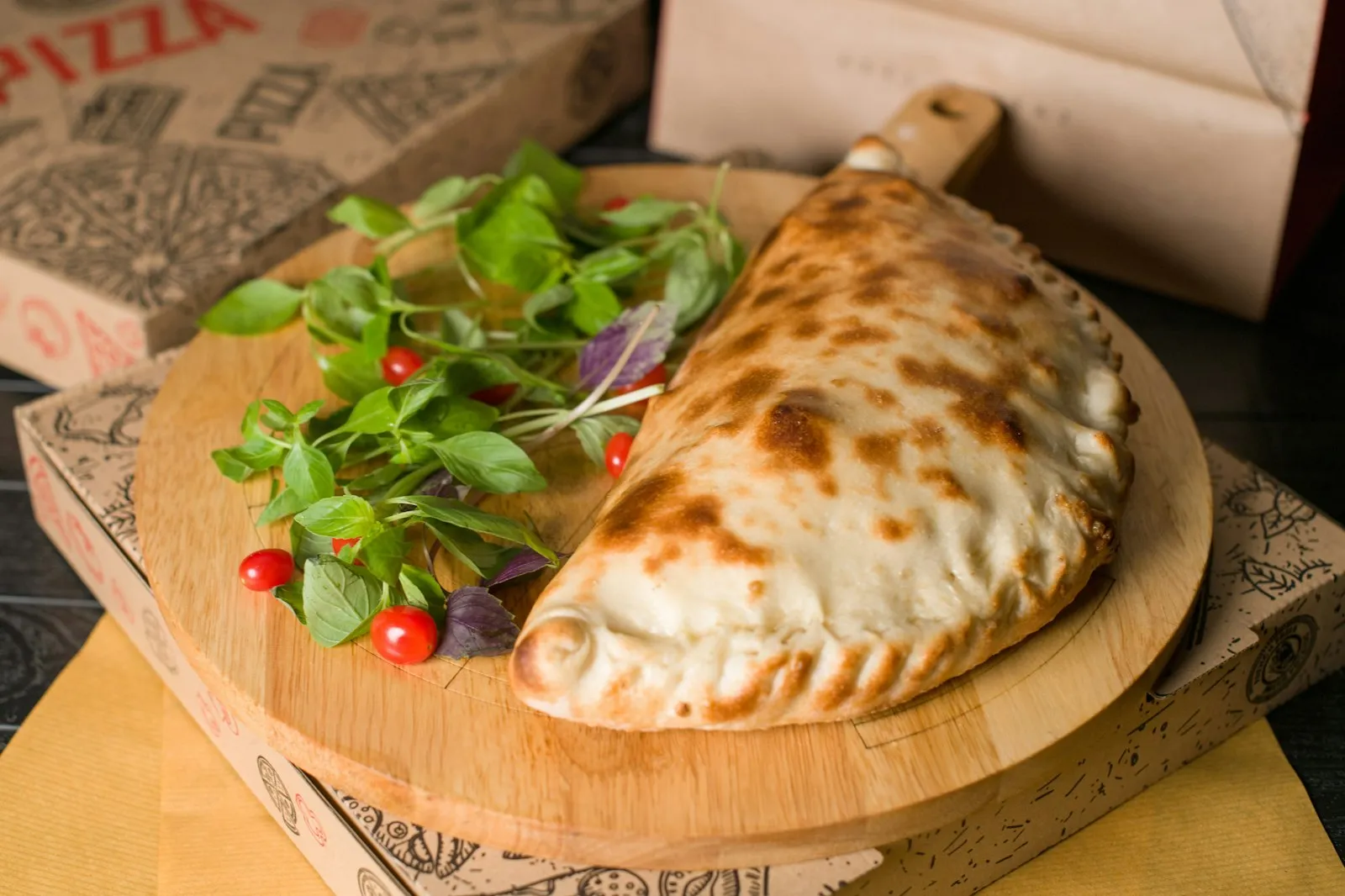 A golden, folded half-moon calzone on a wooden board, the sealed crimped edge that sets a calzone apart from a stromboli