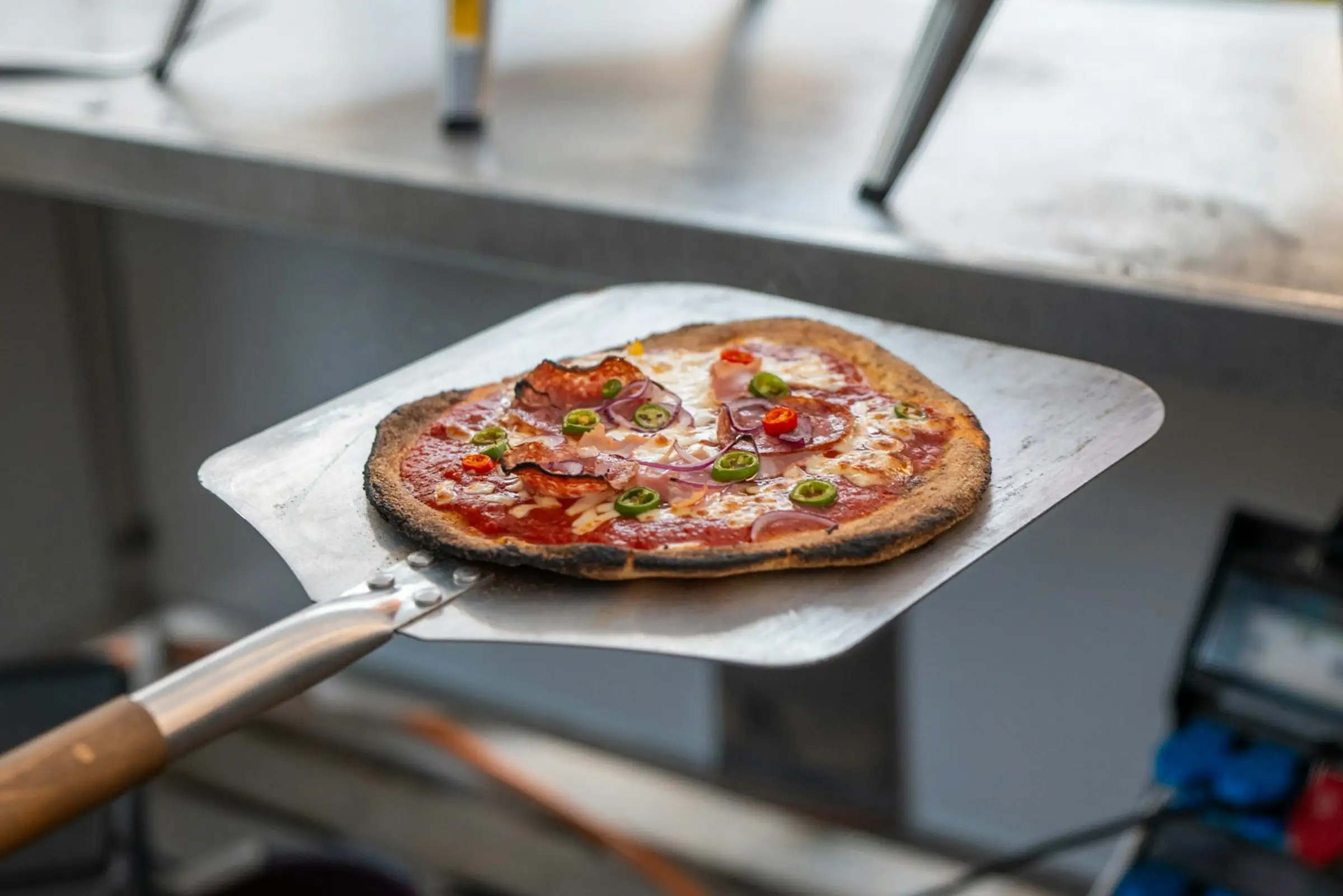 Pizza on a square metal peel with a wooden handle, the metal side of the wood vs metal pizza peel choice