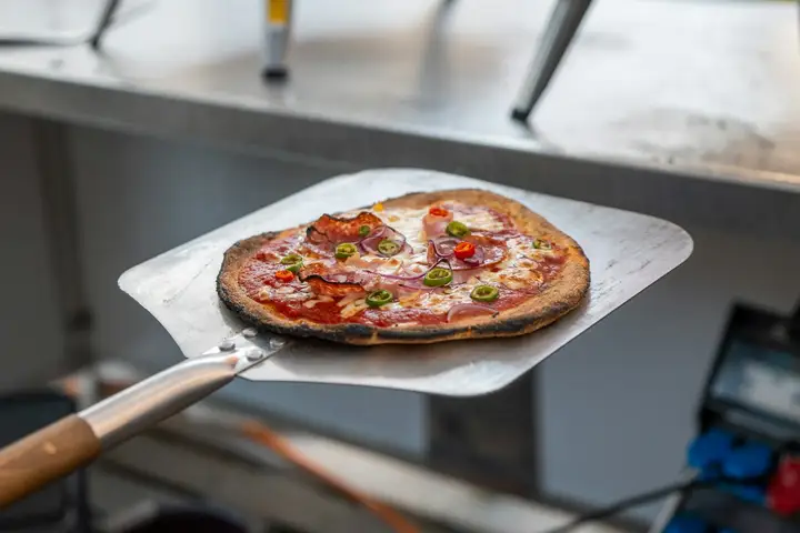 Pizza on a square metal peel with a wooden handle, the metal side of the wood vs metal pizza peel choice